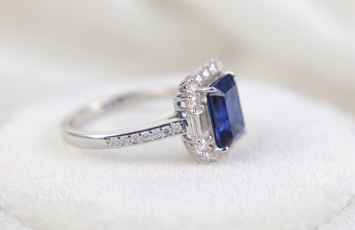 Bague ornée d'une pierre précieuse taille émeraude avec double halo et anneau pavé