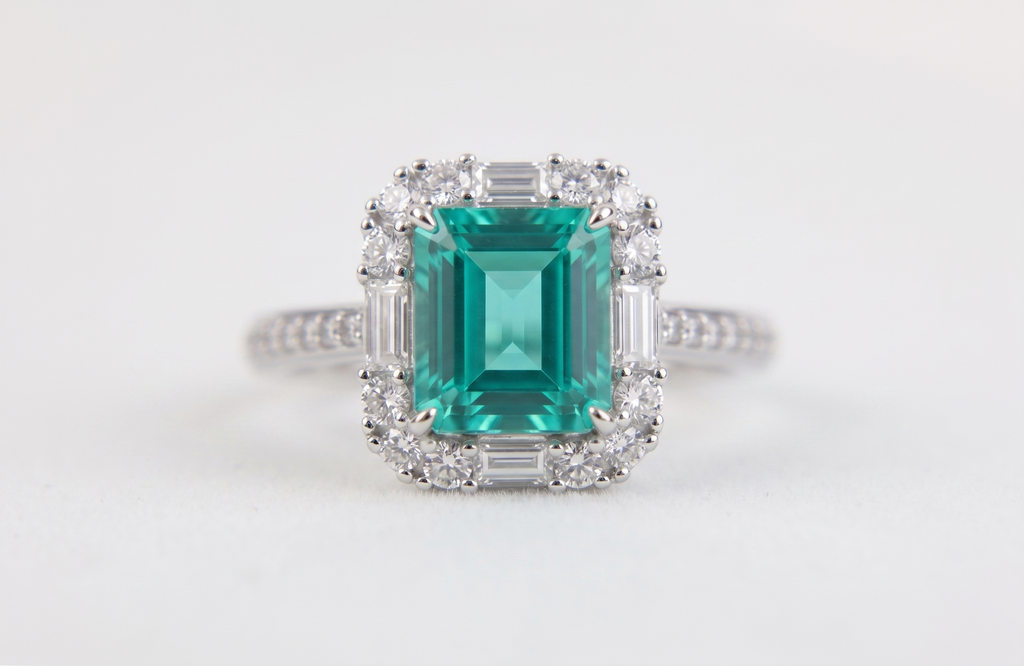 Bague ornée d'une pierre précieuse taille émeraude avec double halo et anneau pavé